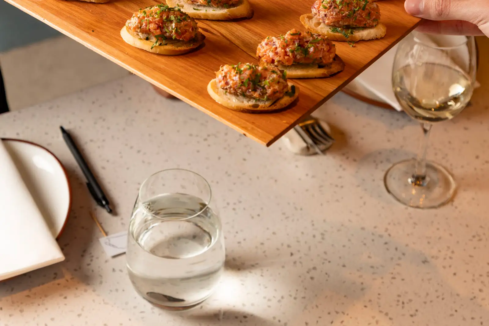Canapés on a board, with the glasses set on the table