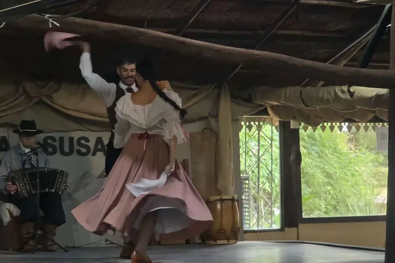 A dancer turning in a long skirt under a thatched roof