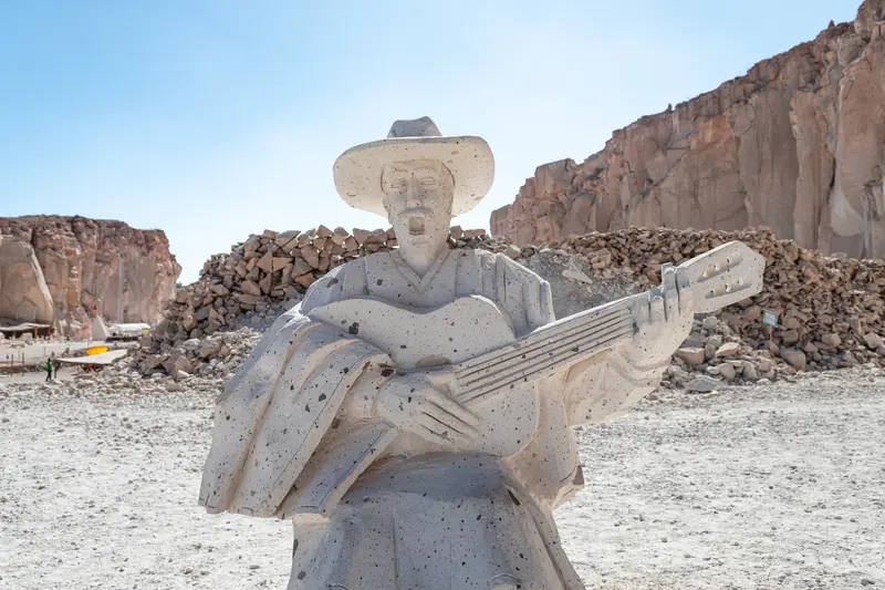 A figure with a guitar carved into the sillar quarry wall