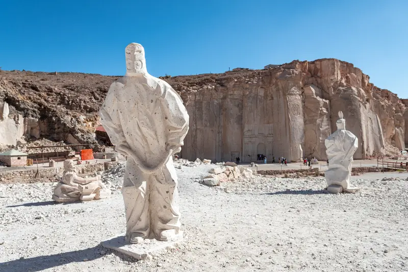 A white figure carved from the sillar rock, standing in the quarry