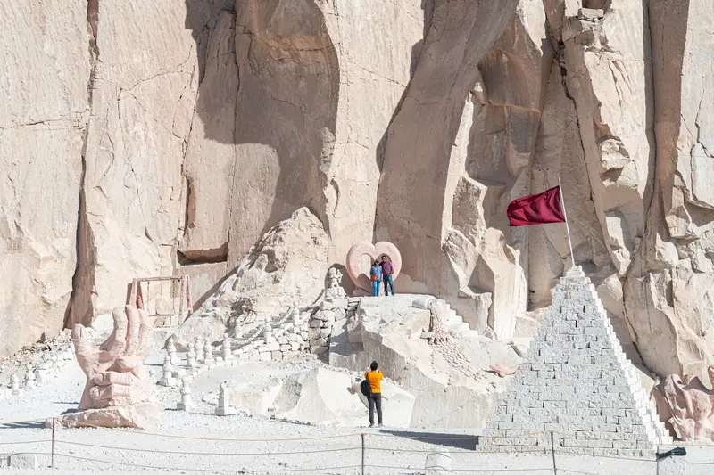 Carvings cut into the quarry wall, with visitors on the steps below