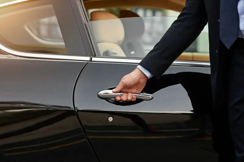 A driver's hand on the door handle of a car