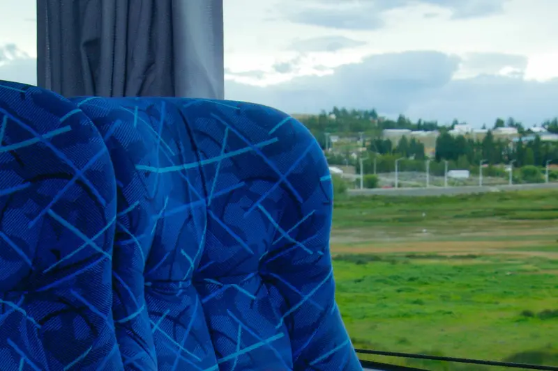 A blue seat cover, with the view through the coach window behind it