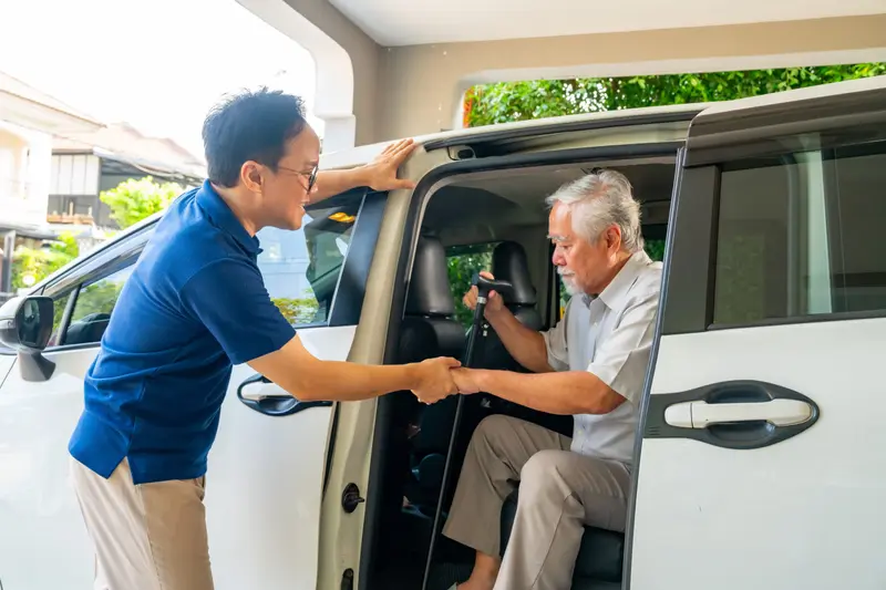 A driver shaking hands with a passenger at the door of a van