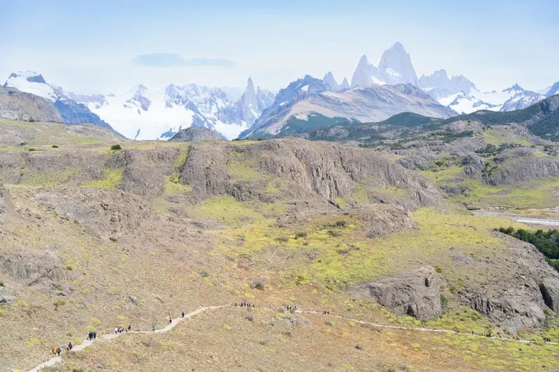 A green ridge with the Fitz Roy range behind it