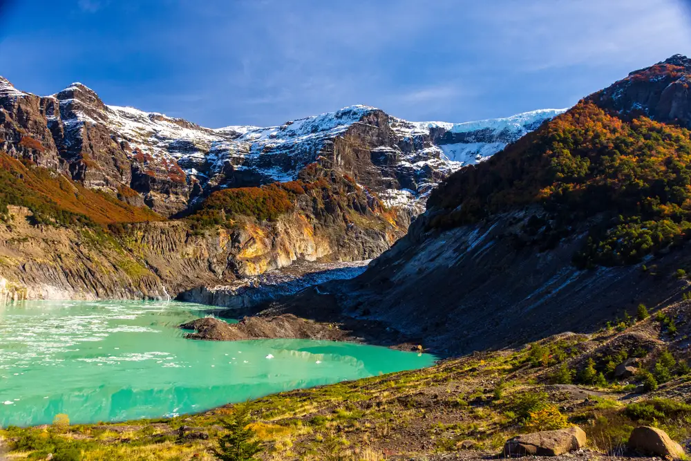 A turquoise lake below dark peaks and a glacier