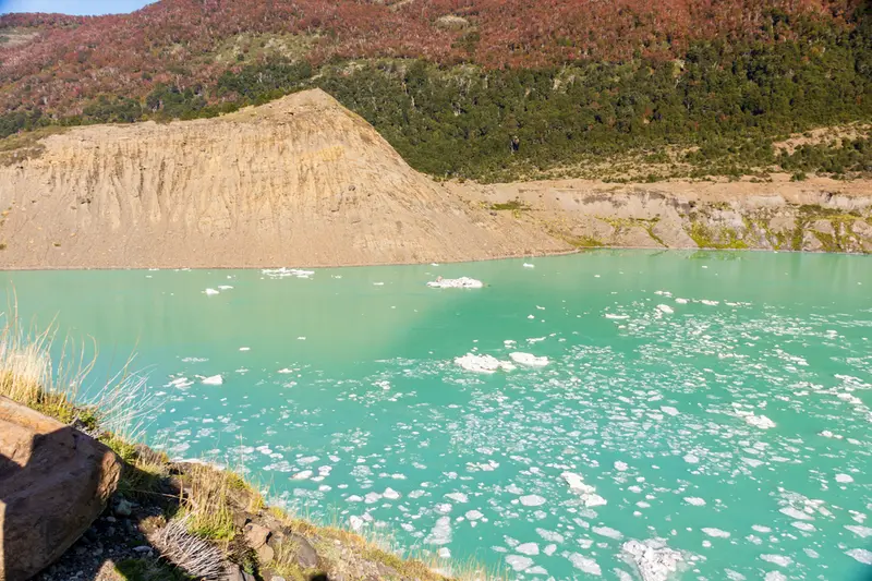 The glacier snout above a turquoise meltwater lake