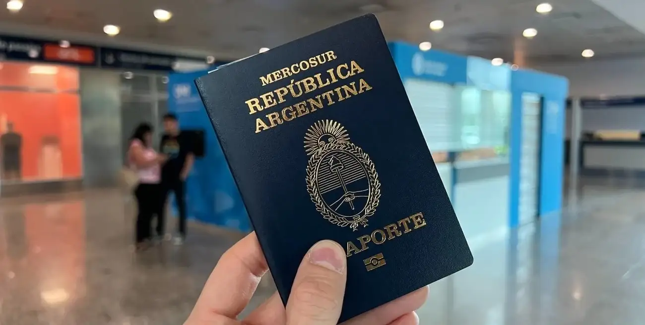 A hand holding an Argentine passport in an airport